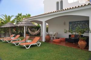 卡巴纳斯·德·塔维拉Luxury 3 bedroom Villa with Private Pool的庭院里摆放着一组椅子和遮阳伞