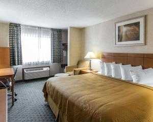 锡达拉皮兹Quality Inn at Collins Road - Cedar Rapids的酒店客房带一张大床和一把椅子