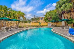 迈阿密湖迈阿密湖拉金塔旅馆及套房的度假村的游泳池配有椅子和遮阳伞