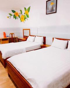 绥和市Hoàng Hà Hotel的客房设有两张带白色床单和桌子的床。