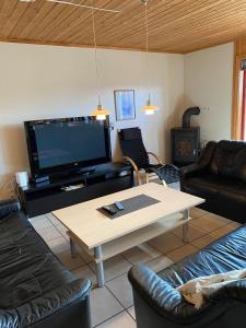 哈山Hafjell Grenda lejligheder的客厅配有桌子和大屏幕电视