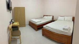 Bạc LiêuKhách Sạn HOÀNG KIM的一间卧室配有两张床、一张桌子和一把椅子