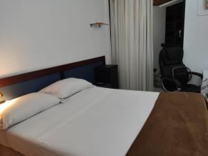 巴西利亚Condomínio Metropolitan - Centro de Brasília A216A的卧室配有一张白色的床、一张桌子和一把椅子