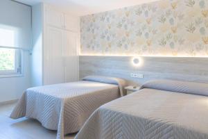 阿罗萨新镇Hotel Leal - La Sirena的花墙间内的两张床