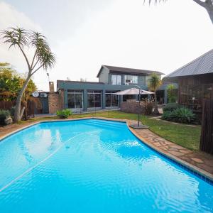 希尔克雷斯特Fever Tree Guesthouse的一座大蓝色游泳池,位于房子前