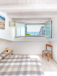 利尼亚诺萨比亚多罗Appartamenti Lignano Sabbiadoro - Villa Ammiraglia的一间卧室设有一张床、一个窗口和一把椅子