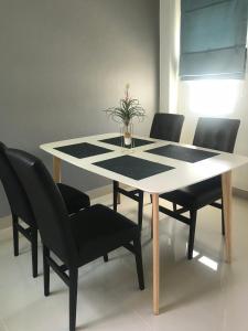 华欣Origin hua hin poolvilla的一张餐桌,配有黑色椅子和花瓶