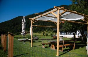 Blejska DobravaRooms Malina的一个带野餐桌和雨伞的木制凉棚