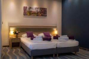 巴尔多巴尔多酒店的一间卧室配有两张带紫色和白色枕头的床