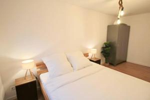 曼海姆Fantastische Moderne und Zentrale Wohnung mit Balkon的一间卧室配有一张带两盏灯的大型白色床。