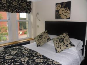 哈罗盖特圆弧精品B&B旅馆的一张带黑白枕头的床和窗户