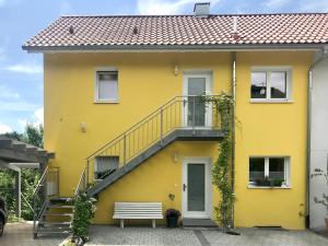 于伯林根Ferienwohnung Sterntaucher的黄色的房子,设有楼梯和长凳