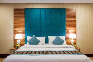 图赖夫Le Park Concord Hotel - Turaif的一间卧室配有一张大床和蓝色床头板
