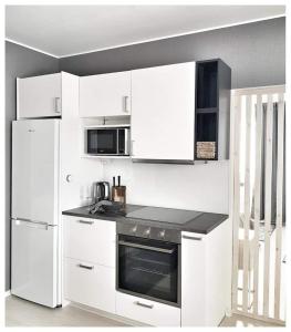 波里Gallen-Kallelankatu 5的白色的厨房配有炉灶和冰箱。