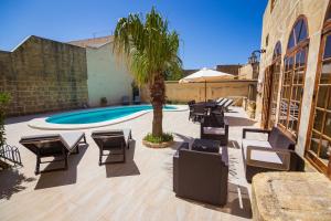 阿尔卜Dar ta' Tumas的一个带椅子的庭院、一个游泳池和一棵棕榈树