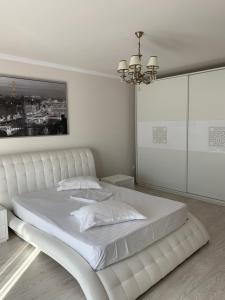 普洛耶什蒂Vila Pati的白色卧室配有一张白色大床和吊灯