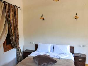 Psarádes友谊旅馆的一间卧室配有一张带白色床单的床和一扇窗户。