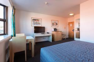 霍巴特Mayfair Plaza Motel and Apartments的配有一张床和一张书桌的酒店客房