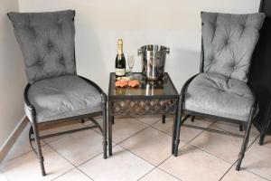 比勒陀利亚Batter Boys Guest House的两把椅子和一张桌子及一瓶香槟