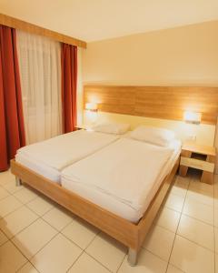 库克利卡泽莱纳朴塔假日酒店的一间卧室配有一张大床和木制床头板