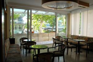 里米尼Hotel Arno的餐厅设有桌椅和大窗户。