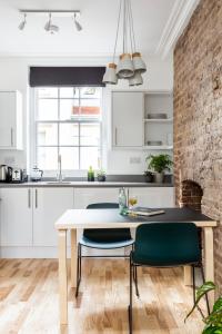 伦敦Bloomsbury By Viridian Apartments的厨房配有白色橱柜和桌椅