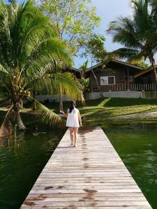 弗洛勒斯Hotel Santa Barbara Tikal的一位在水面上木桥上行走的女人