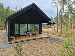 埃克奈斯Kopparö Tammisaari的黑色小屋设有木甲板和桌子
