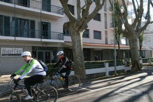 班约莱斯阿斯特酒店的两个人骑着自行车沿着大楼前的街道骑着
