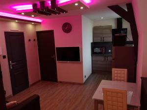 梅尔·莱斯·拜恩斯Appartement moderne avec balnéothérapie的一间带粉色墙壁的客厅和一间厨房