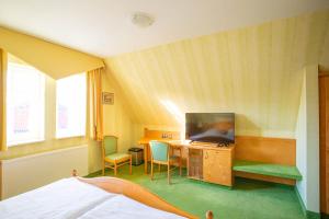 埃施韦格Hotel-Pension Eschwege的客房设有1张床、1台电视和1张书桌。