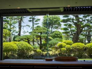 谏早市Hotel Flags Isahaya Nagasaki的享有花园树木和灌木的窗户