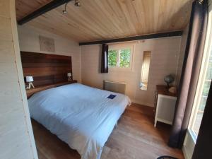 Fichous-RiumayouLe lodge sur pilotis的一间卧室设有一张带木制天花板的大床