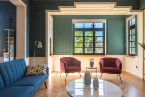 雅典Moon And Stars Athens的客厅配有蓝色的沙发和2把红色的椅子