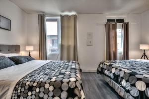 蒙特利尔100 METERS to SUBWAY - Montcalm condos的一间卧室设有两张床和两个窗户。