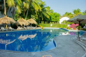 圣克鲁斯华特库Hotel Castillo Huatulco & Beach Club的毗邻度假酒店的带椅子和遮阳伞的游泳池