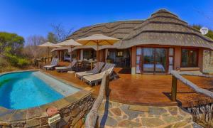 马迪克韦狩猎保护区Motswiri Private Safari Lodge的茅草屋顶和游泳池的房子