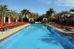 拉斯维加斯M Spa度假酒店&赌场的一个带红色椅子和棕榈树的大型游泳池