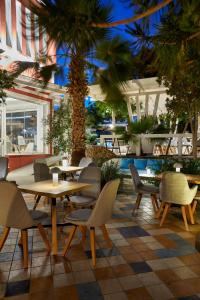 卡马利蓝色海洋酒店的一间设有桌椅的餐厅,种植了棕榈树