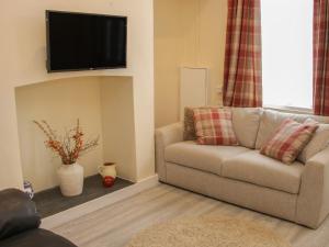 兰戈伦Whitewater Cottage的客厅配有沙发和墙上的电视