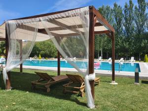 San Miguel de las DueñasHotel rural Finca Vivaldi Nature & Spa的游泳池旁的凉亭下方设有两把椅子