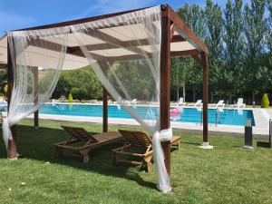 San Miguel de las DueñasHotel rural Finca Vivaldi Nature & Spa的游泳池旁的凉亭下方设有两把椅子