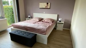 蒙绍eifelbleibe的一间卧室配有一张带粉色床单和黑色凳子的床。