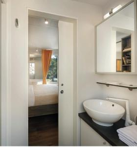 班约勒Victoria Mobilehome in Padova Premium Camping Resort的一间带水槽的浴室和一张带镜子的床