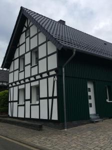 施莱登Fewo Eifeler Edelsteine „Aquamarin“的一座黑白的建筑,拥有绿色的屋顶