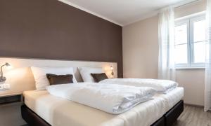 奥伯丁Gästehaus Lemerhof的卧室配有一张带白色床单的大床和窗户。
