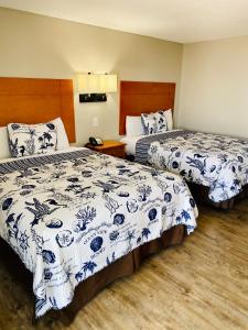 翡翠岛Oceanview Inn - Emerald Isle的酒店客房带两张带蓝白床单的床。