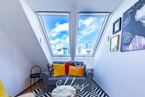 维也纳Eddie’s Design Apartments的客房设有窗户和蓝色沙发,配有色彩缤纷的枕头