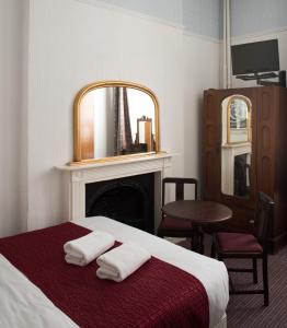 伦敦圣亚詹斯酒店的一间卧室配有一张床、镜子和椅子