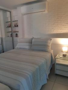 福塔莱萨LIV INN Apartamento na Beira-Mar Fortaleza的配有枕头的白色床和带灯的床头柜